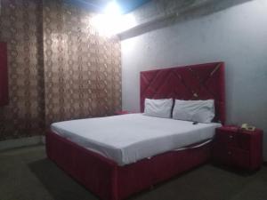 Schlafzimmer mit einem großen Bett mit einem roten Kopfteil in der Unterkunft Safari Hotel in Lahore