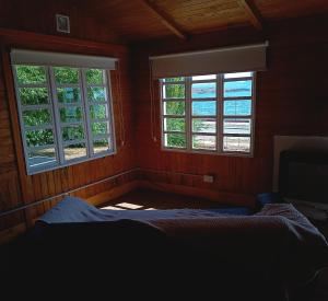 - une chambre avec deux fenêtres et un lit dans l'établissement Cabaña Los Cisnes, à El Calafate