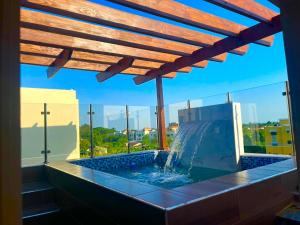 a swimming pool with a wooden roof and a fountain at Lujoso jacuzzi privado mi cell 347-864 -3082 in San Francisco de Macorís