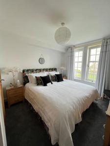 - une chambre avec un grand lit blanc et des fenêtres dans l'établissement Central St Andrews 2 bed apartment, à St Andrews