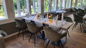 uma sala de jantar com uma mesa longa e cadeiras em Hotel Müllers im Waldquartier em Bad Essen