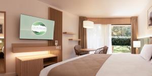 a hotel room with a bed and a tv at Résidence Hôtelière les Acanthes in Hossegor
