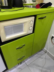 eine grüne Küche mit einer Spüle und einer Mikrowelle in der Unterkunft La Perle du Sahel avec clé personnel du portail in Niamey