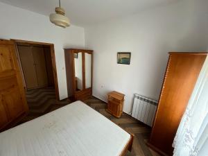 a bedroom with a white bed and a wooden cabinet at Grande Apartment in Tsarevo