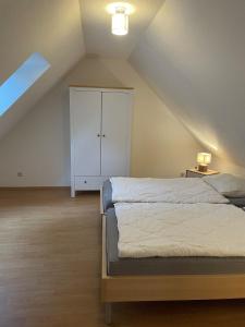 a attic bedroom with a bed and a white cabinet at Ferienglück - 100 m zum Strand - Garten & Privatterrasse - Hund willkommen in Ostseebad Karlshagen