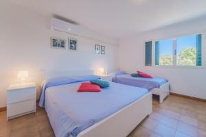 2 camas en una habitación blanca con almohadas azules y rojas en Casa William - Villa e 2 Dependance, en Porto Azzurro