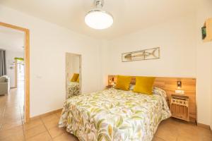 ein Schlafzimmer mit einem Bett mit gelben Kissen in der Unterkunft Apartamento Playa La Barrosa in Chiclana de la Frontera + 40 Fotos