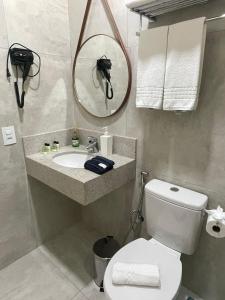 a bathroom with a toilet and a sink and a mirror at Pousada Thermas das Montanhas in Águas de Lindóia