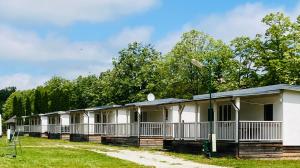 a row of mobile homes with trees in the background at Polzer CAMPING BÜKFÜRDŐ in Bük