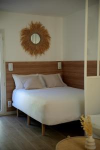 una camera da letto con un grande letto bianco e uno specchio di La paillotte - Studio terrasse proche tram a Montpellier