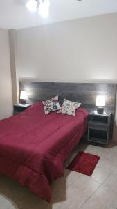 a bedroom with a red bed with two pillows on it at Departamentos Centro in Belén