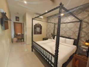 a bedroom with a black canopy bed with white sheets at Chola Heritage Resort in Kāraikkudi
