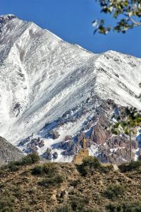 a snow covered mountain with a person standing in front of it at El Torreón Lodge in Potrerillos