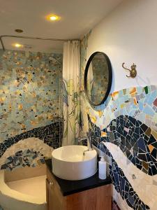 uma casa de banho com um lavatório e uma parede em mosaico em Pension Solvang em Rønne