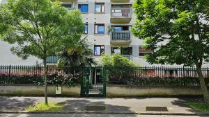 une clôture devant un bâtiment avec un arbre dans l'établissement Appartement avec balcon proche Paris & Disneyland, à Champigny-sur-Marne