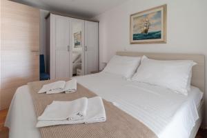 um quarto com uma cama branca e toalhas em Bungalov Medanic - Private Pool em Privlaka
