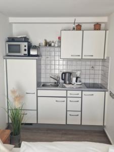 a kitchen with white cabinets and a microwave at Appartement Haus Sonnenheim in Zell am See
