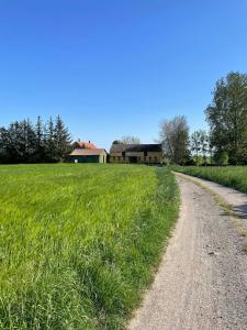 uma estrada de terra num campo com uma casa ao fundo em Pension Solvang em Rønne