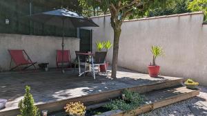 patio con tavolo, sedie e ombrellone di Petite Maison indépendante. a Béziers