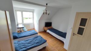 ミエルノにあるPokoje w Mielnie "Polikarp"の青いベッド2台と窓が備わる客室です。