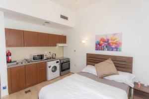 a small bedroom with a bed and a kitchen at Fully Furnished Studio In JVC RL in Dubai