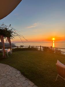 ein Sonnenuntergang über dem Meer mit Stühlen und einem Zaun in der Unterkunft villa incanto in Zambrone