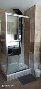 La salle de bains est pourvue d'une douche avec une porte en verre. dans l'établissement Appartement de standing : 2 chambres, à Raismes