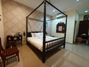 1 dormitorio con cama con dosel y mesa en Chola Heritage Resort en Kāraikkudi