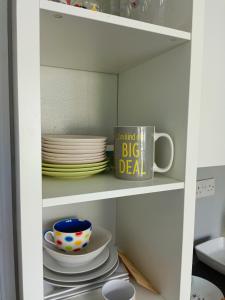 a white cabinet with plates and a mug on it at Cozy stay in Southampton