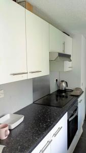 uma cozinha com armários brancos e um balcão preto em Cozy stay em Southampton