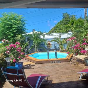 una piscina en una terraza de madera con sillas y flores en Villa de 2 chambres avec vue sur la mer piscine privee et jacuzzi a Bouillante, en Bouillante