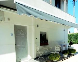 a white building with a door and a table and chairs at villa Heljos apartaments in Vlorë