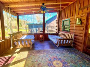 a porch of a cabin with two beds and a ceiling fan at River Dreaming in Townsend