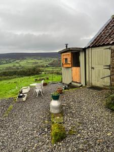 a small shed with a table and a chair next to it at Shepherd's Hut Bilsdale in Chop Gate