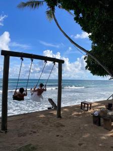 dos personas jugando en un columpio en la playa en Ocean Talpe Villa, en Talpe