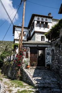 a stone building with a door and flowers in front at Ινω Superior Suite 1856 Makrinitsa Pelion in Makrinitsa