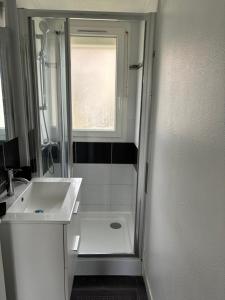 ein Badezimmer mit Waschbecken und Dusche mit Fenster in der Unterkunft Maison de pêcheur in Bernières-sur-Mer