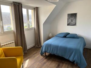 Schlafzimmer mit einem Bett mit blauer Bettwäsche und einem Stuhl in der Unterkunft Maison de pêcheur in Bernières-sur-Mer