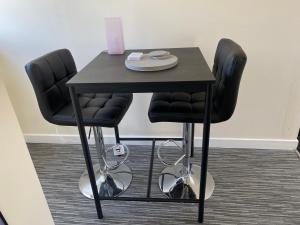 una mesa con dos sillas negras y una mesa negra en WHITEHILL STABLES, en Kirknewton