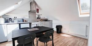 Cozy Room in Modern House near Nottingham في نوتينغهام: مطبخ مع طاولة سوداء وكراسي
