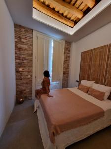 a child sitting on a bed in a bedroom at Antiquari de Blanes Apartamento Boutique en la Costa Brava in Blanes