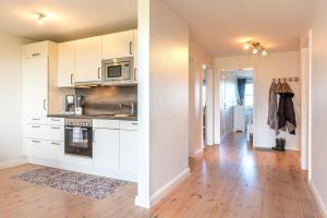 a kitchen with white cabinets and a wooden floor at Leefke in Goting +6 photos
