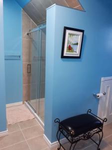 uma casa de banho com uma cabina de duche em vidro e um banco em Dans les draps de Morphee em Campbellton