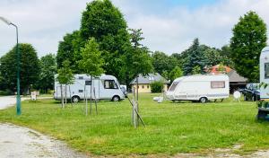 two recreational vehicles parked in a field with trees at Polzer CAMPING BÜKFÜRDŐ in Bük