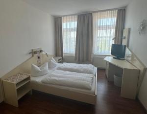 a bedroom with a bed and a desk with a television at Hotel Perle am Bodden in Ribnitz-Damgarten