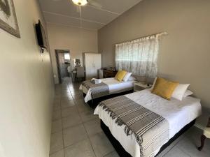 duas camas num quarto de hotel com um quarto em Oppi Draai Guesthouse em Oudtshoorn