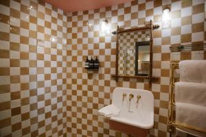 een betegelde badkamer met een wastafel en een spiegel bij The Grain Store in Sutton Bonington
