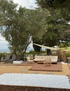 ein Sofa und Stühle auf einer Terrasse mit Bäumen in der Unterkunft Spereto Pendolino, pool, nature and view in Montaione