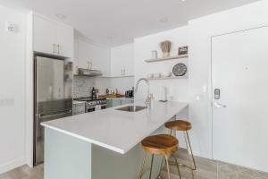 a white kitchen with a counter and two stools at Northeka208 in Quebec City