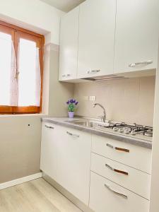 een keuken met witte kasten en een wastafel bij Oasi Verde Acqua - Country Porto Rotondo in Porto Rotondo